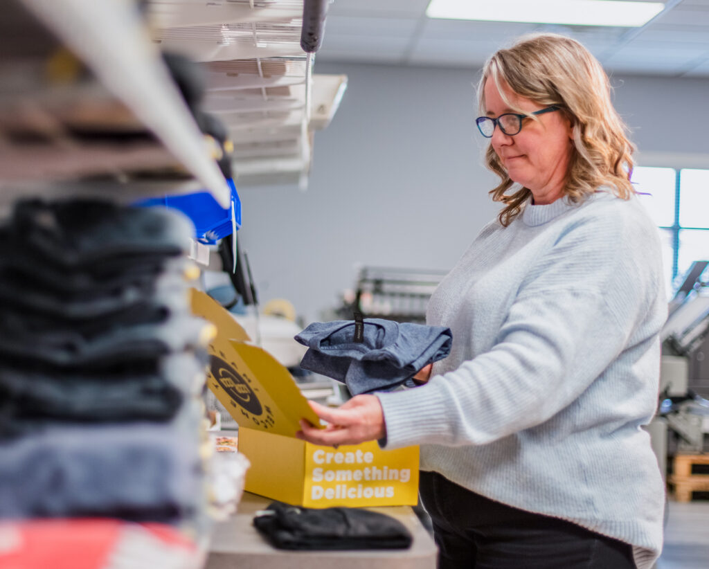 Woman packing items in a welcome kit box.