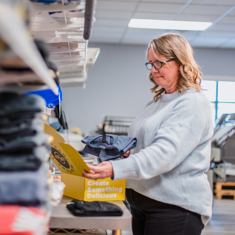 Woman packing items in a welcome kit box.