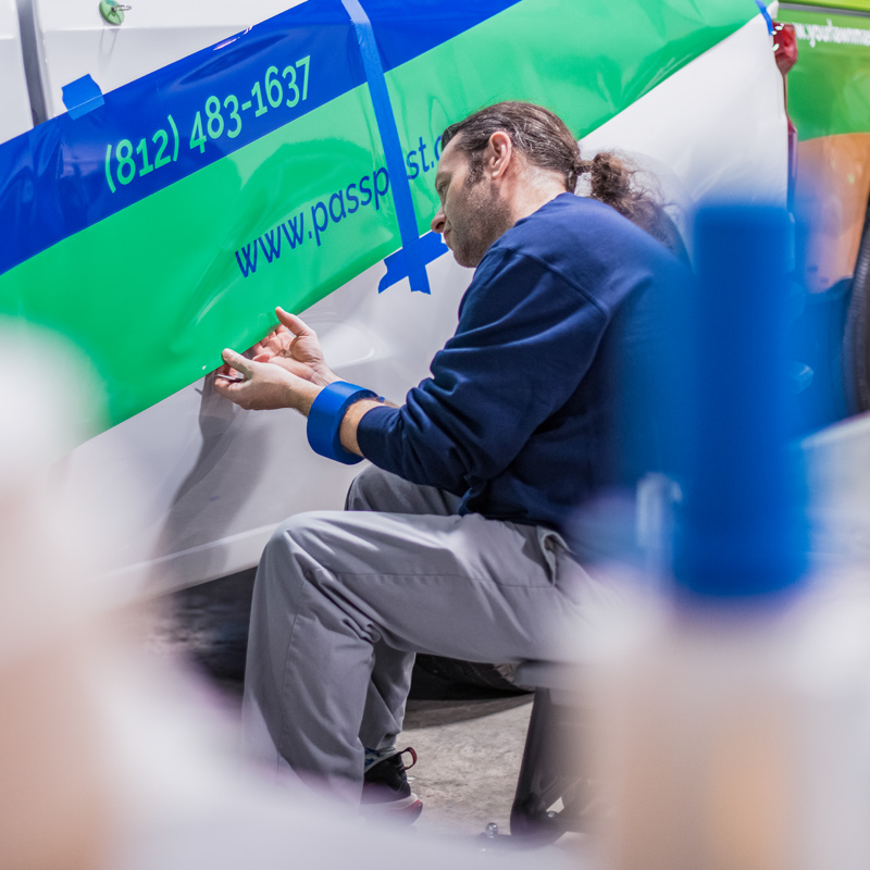 SLADE employee applying vehicle lettering.