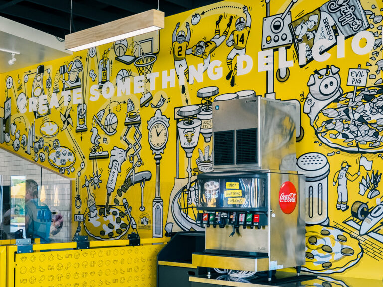 Yellow Azzip wall mural with food illustrations and the words "Create Something Amazing."