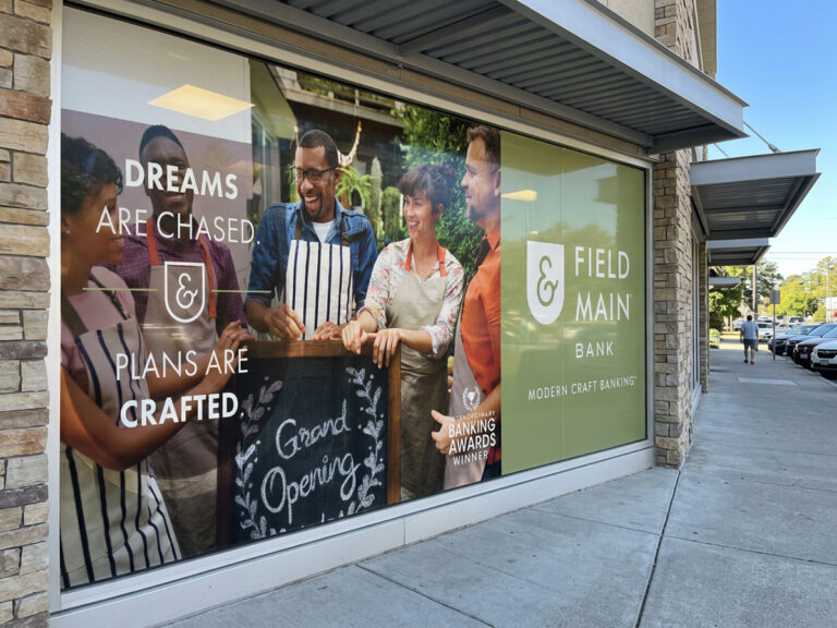 Field & Main Bank window graphics featuring people, the bank logo and a grand opening message.