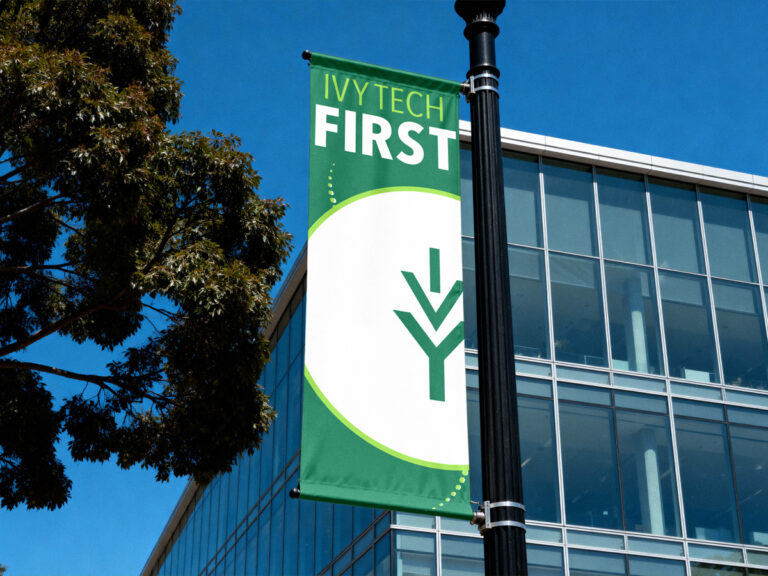 Green and white "Ivy Tech First" banner mounted on a campus lamppost.