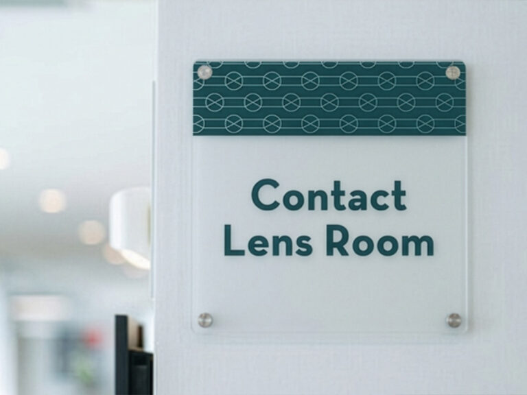Wall-mounted "Contact Lens Room" sign with a patterned green header.