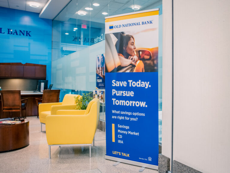 Old National Bank retractable banner reading "Save Today. Pursue Tomorrow." in a bank lobby.