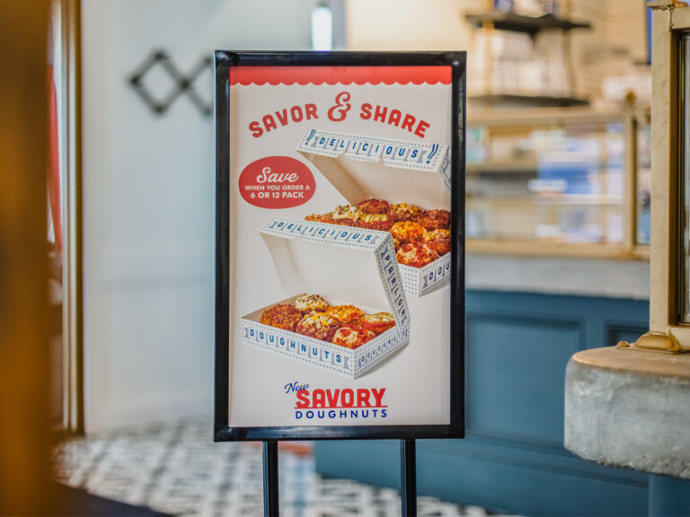 Freestanding Parlor Doughnuts sign displaying savory doughnuts and "Savor & Share."