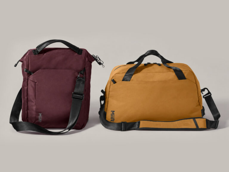 Burgundy shoulder bag and mustard duffel bag with black handles and straps.