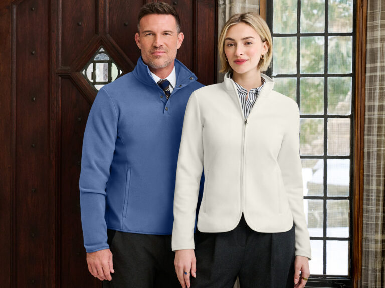 Two people modeling a blue quarter-zip sweater and a cream zip-front jacket over collared shirts.