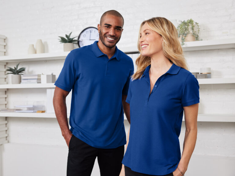Two people wearing blue polo shirts and dark trousers.