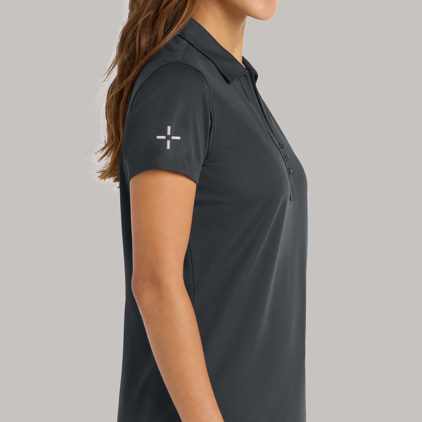 Side view of a charcoal polo with a small geometric logo on the sleeve.