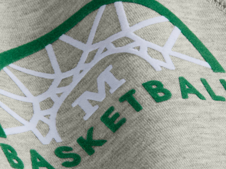 Raised white basketball-net design with green lettering printed on gray fabric.