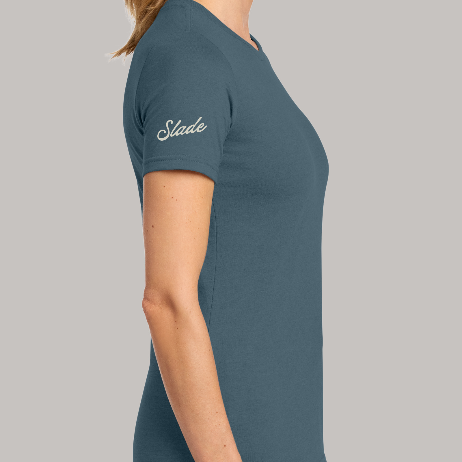 Side view of a dark teal T-shirt with Slade lettering printed on the sleeve.