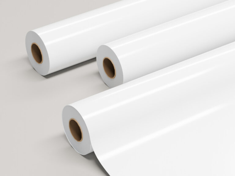Three rolls of glossy white sign material, with one partly unrolled.
