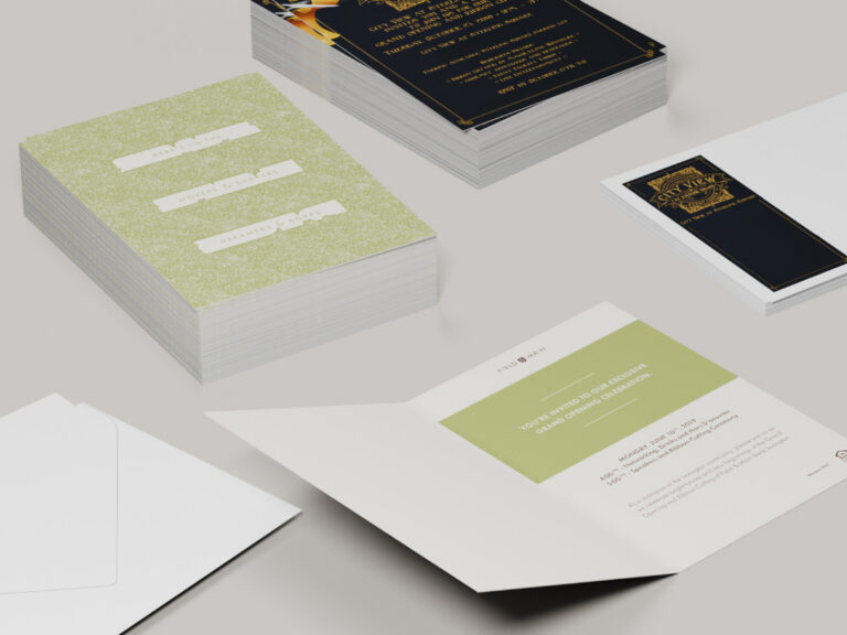 Printed grand opening invitations in green and black-and-gold designs, with matching envelopes.