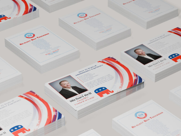 Stacks of printed political campaign mailers for Michael Bell and Ben Trockman in red, white and blue.
